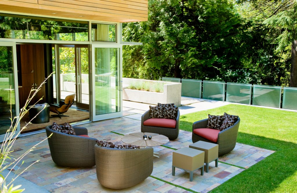A backyard interlocking patio with a winding stone path and designer furniture